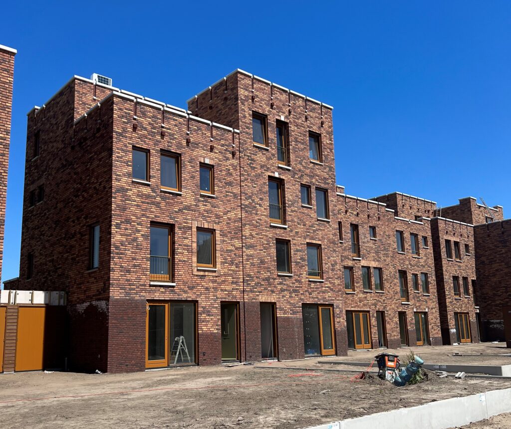 Net nieuw gebouwde rijtjeswoningen met donkere bakstenen en elke woning heeft platte daken en verschillende hoogtes.